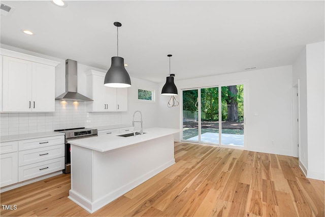 kitchen with electric stove, backsplash, a sink, light wood-type flooring, and wall chimney exhaust hood