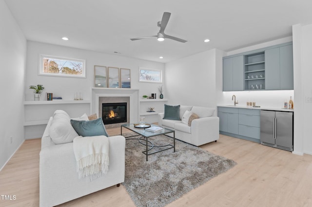 living room featuring light wood-style floors, recessed lighting, indoor wet bar, and a fireplace