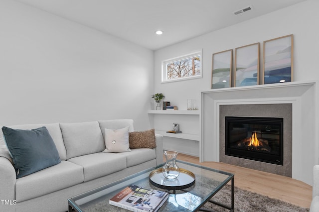 living area featuring recessed lighting, visible vents, wood finished floors, and a glass covered fireplace