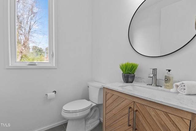 half bath featuring tile patterned flooring, baseboards, vanity, and toilet