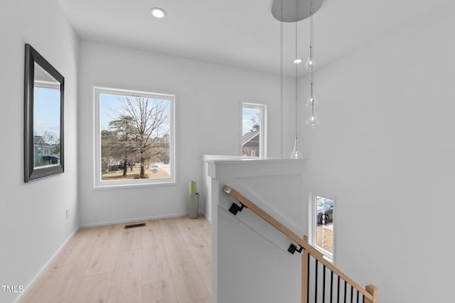 hall featuring light wood-style flooring, recessed lighting, visible vents, baseboards, and an upstairs landing