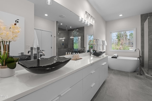 bathroom featuring double vanity, a soaking tub, a sink, a shower stall, and tile patterned floors