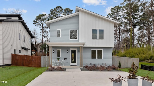 view of front of home with covered porch, fence, a front lawn, and board and batten siding