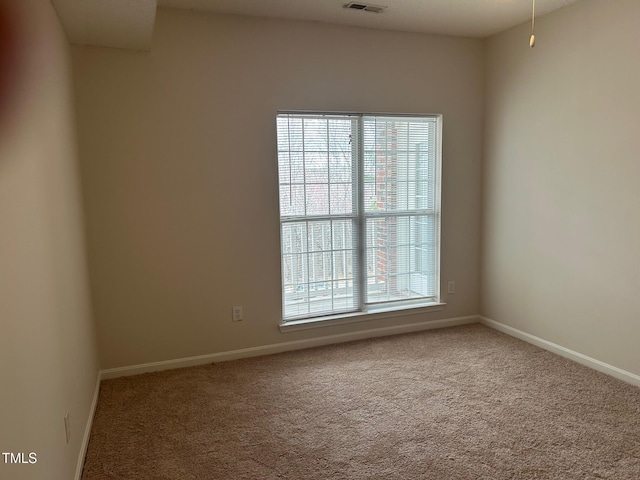 spare room with carpet flooring, visible vents, and baseboards