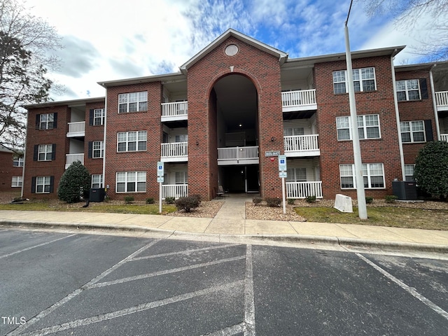 view of building exterior featuring uncovered parking and central AC unit