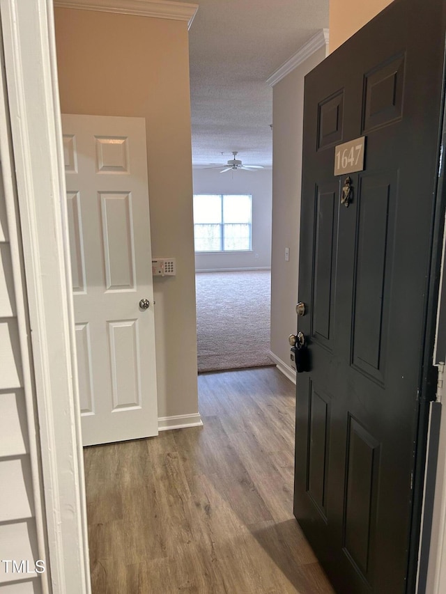 foyer featuring ceiling fan, baseboards, wood finished floors, and crown molding