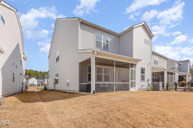 back of property with a sunroom, a yard, and central AC