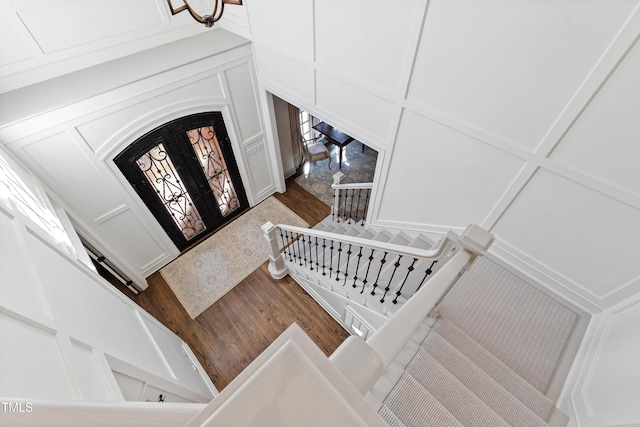 entryway featuring stairs, a decorative wall, wood finished floors, and french doors