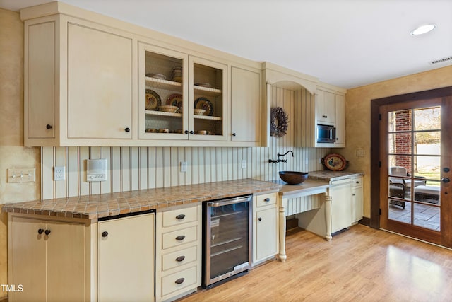 bar featuring light wood-style flooring, wine cooler, visible vents, and stainless steel microwave