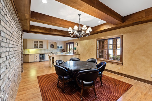 dining space featuring beam ceiling, a notable chandelier, light wood-style flooring, beverage cooler, and baseboards