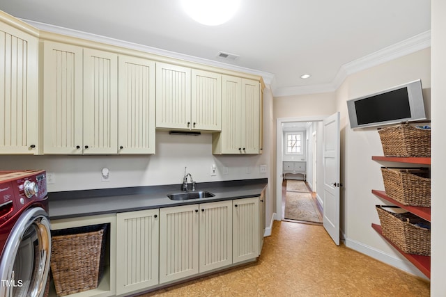 kitchen featuring washer / dryer, visible vents, dark countertops, cream cabinetry, and a sink