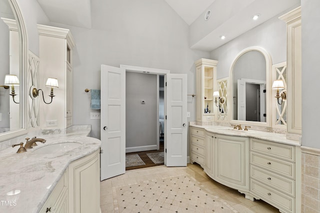 full bathroom featuring a sink, tile patterned flooring, high vaulted ceiling, and two vanities