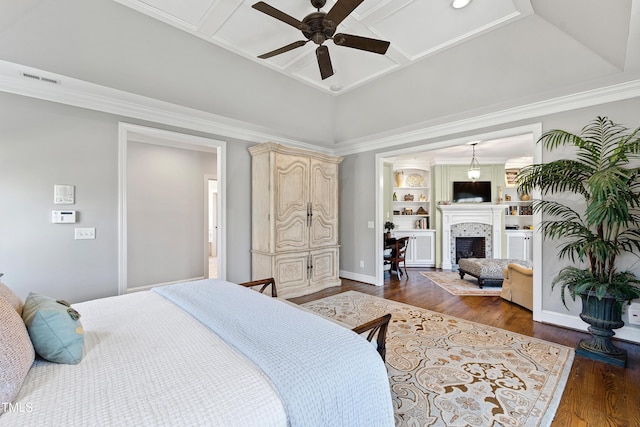 bedroom featuring coffered ceiling, crown molding, a fireplace, and wood finished floors