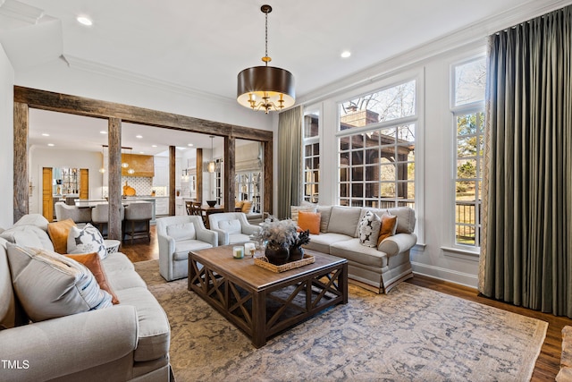 living room featuring an inviting chandelier, ornamental molding, wood finished floors, and recessed lighting