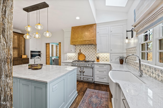 kitchen featuring backsplash, oven, light stone countertops, premium range hood, and a sink