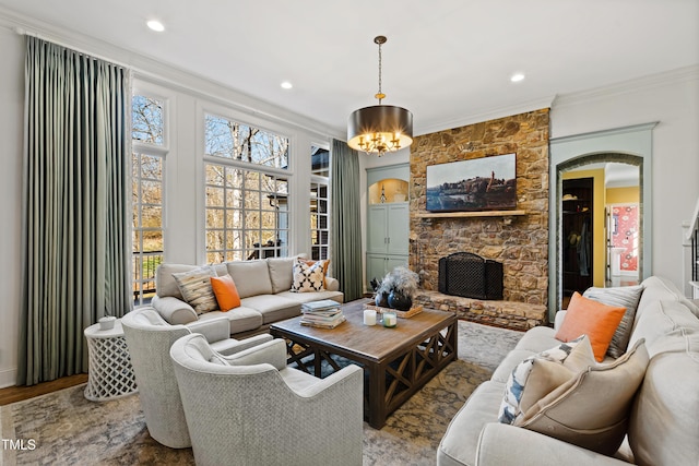 living room with arched walkways, wood finished floors, crown molding, and a stone fireplace