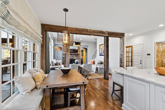 dining space featuring dark wood-style floors, recessed lighting, crown molding, and a stone fireplace