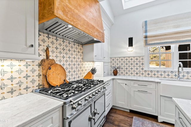 kitchen featuring premium range hood, stove, backsplash, and white cabinetry