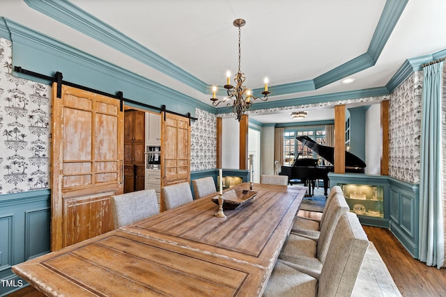 dining room with a barn door, wainscoting, and a raised ceiling