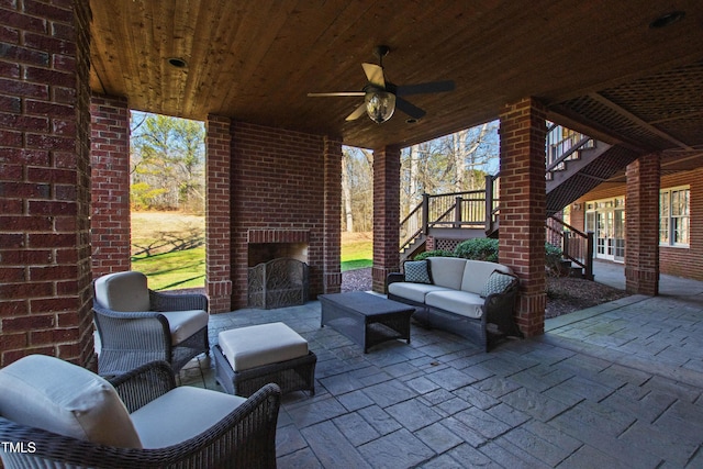 view of patio with a ceiling fan, stairway, and an outdoor living space with a fireplace