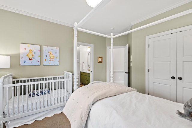 bedroom with a crib, ornamental molding, and a closet