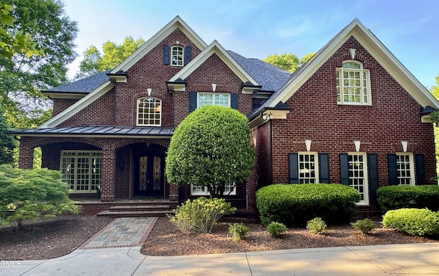 view of front of property with a porch, a standing seam roof, and brick siding