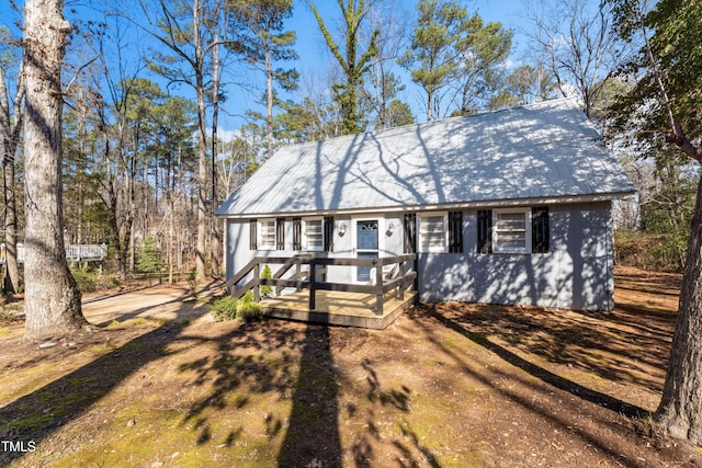 view of front of property with metal roof, driveway, and a wooden deck