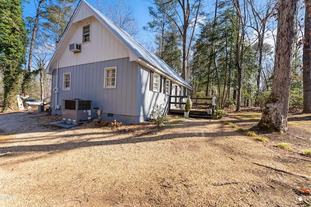 view of property exterior with crawl space, a wooden deck, a wall mounted AC, and central air condition unit