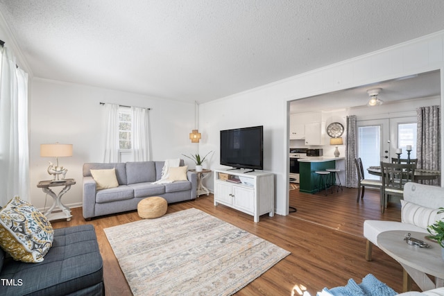 living area featuring crown molding, a textured ceiling, wood finished floors, and french doors