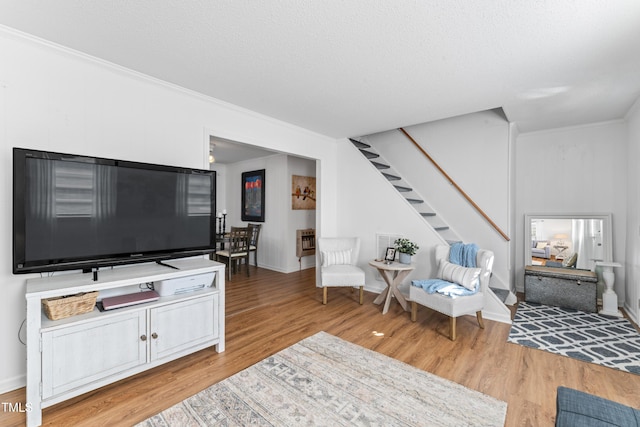 living area featuring a textured ceiling, wood finished floors, stairway, heating unit, and crown molding