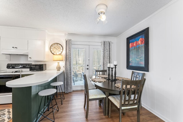 dining area featuring a textured ceiling, french doors, crown molding, and wood finished floors