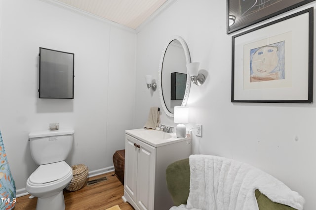 bathroom with visible vents, toilet, ornamental molding, vanity, and wood finished floors