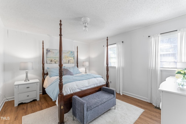 bedroom featuring a textured ceiling, baseboards, and light wood-style floors