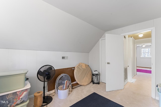 interior space featuring carpet floors, visible vents, and vaulted ceiling