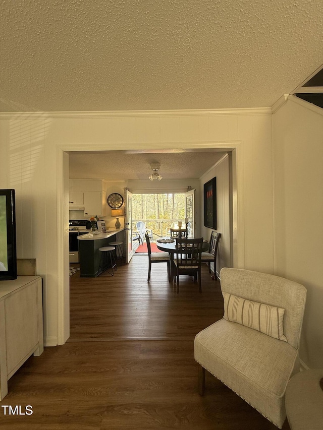 interior space with a textured ceiling, ornamental molding, and dark wood-type flooring