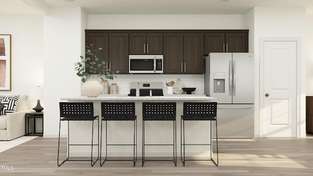 kitchen featuring light stone counters, electric stove, tasteful backsplash, fridge with ice dispenser, and a kitchen bar