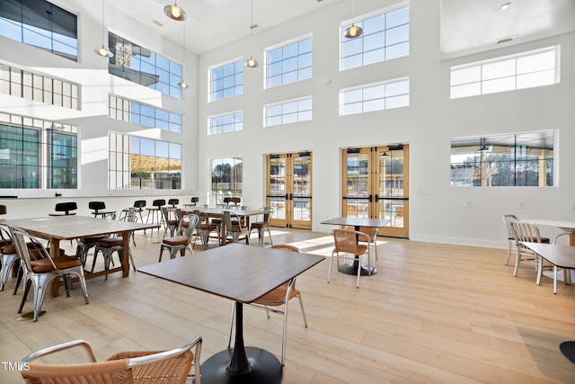 dining space featuring french doors, baseboards, and light wood finished floors