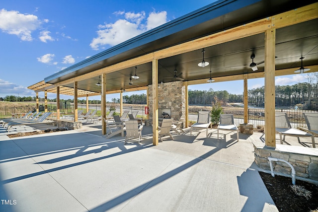 view of patio / terrace with a ceiling fan, fence, and a stone fireplace