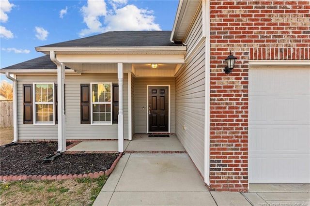 property entrance featuring brick siding, roof with shingles, and an attached garage