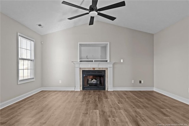 unfurnished living room featuring a tile fireplace, wood finished floors, visible vents, baseboards, and vaulted ceiling