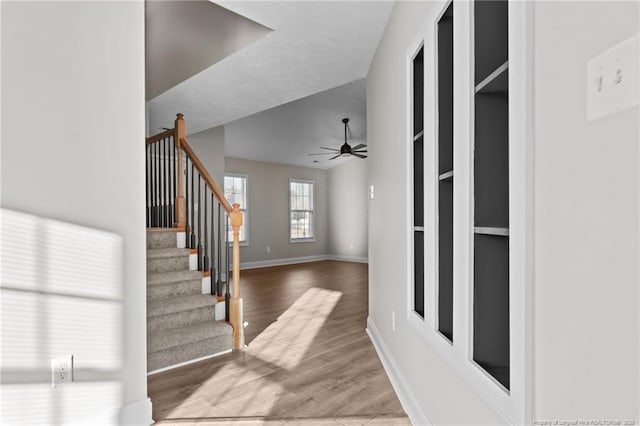 entryway featuring a ceiling fan, wood finished floors, baseboards, and stairs