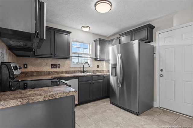 kitchen with stainless steel fridge, range, dark countertops, a sink, and backsplash