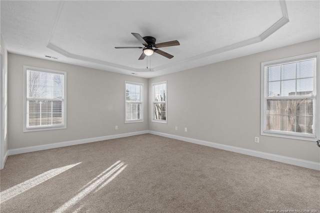 carpeted spare room with a ceiling fan, a tray ceiling, and baseboards