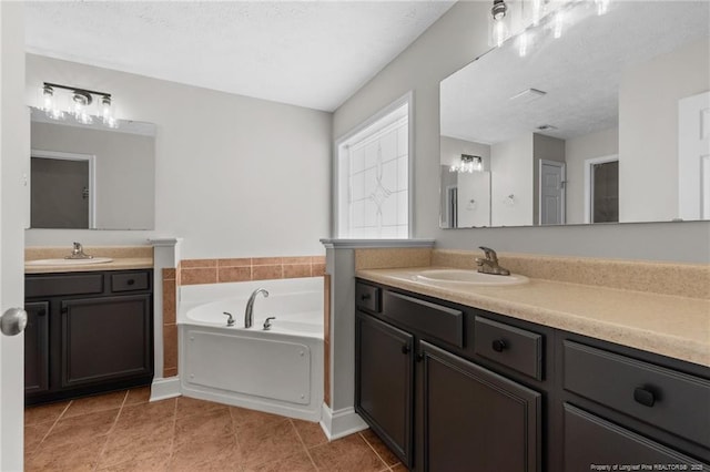 bathroom featuring a garden tub, tile patterned flooring, two vanities, and a sink