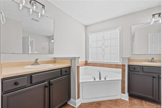 full bath featuring two vanities, a garden tub, a sink, and tile patterned floors