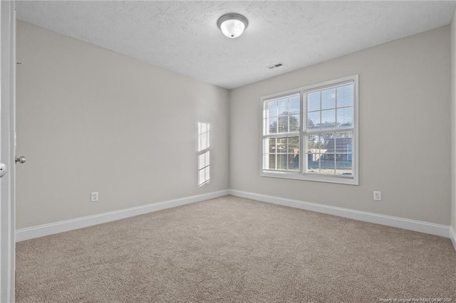 carpeted spare room featuring visible vents, baseboards, and a textured ceiling