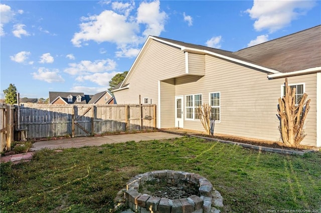 back of property featuring a fenced backyard, a fire pit, and a yard