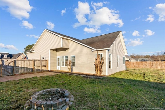 back of house featuring a fire pit, a yard, and fence