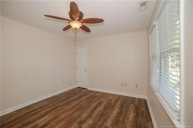 spare room featuring visible vents, a textured ceiling, baseboards, and dark wood-style flooring