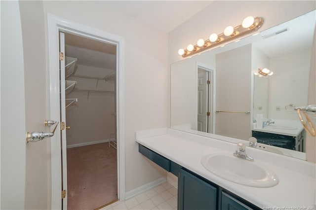 full bathroom with visible vents, baseboards, a walk in closet, and vanity